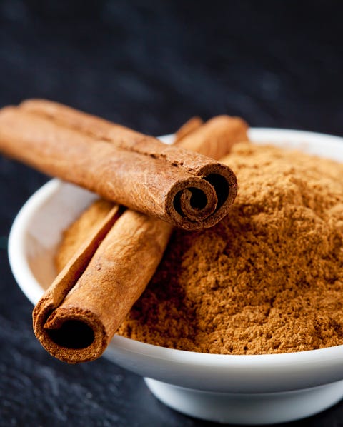 Bowl of cinnamon powder and two cinnamon sticks Bowl of cinnamon powder and two cinnamon sticks