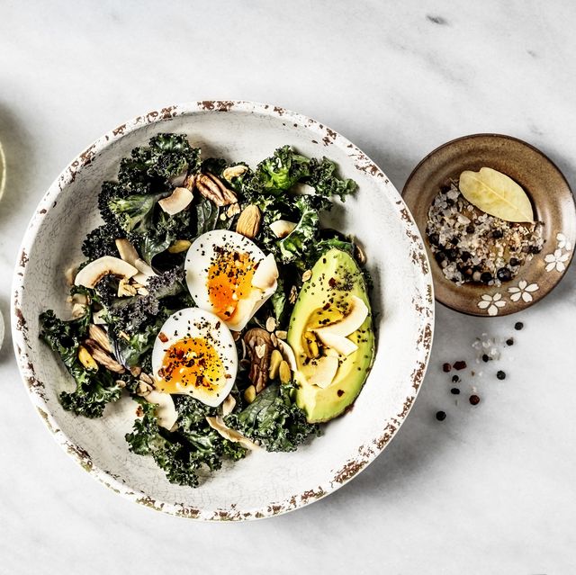 High Protein Breakfasts - Bowl of kale salad with boiled eggs and avocado on white background