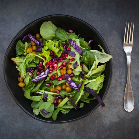 bowl of mixed leaf salad with pomegranate seed, red cabbage and roasted curcuma chick peas