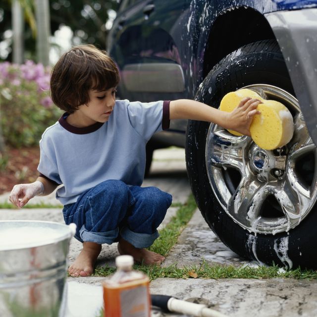 boy washing car wheel with sponge