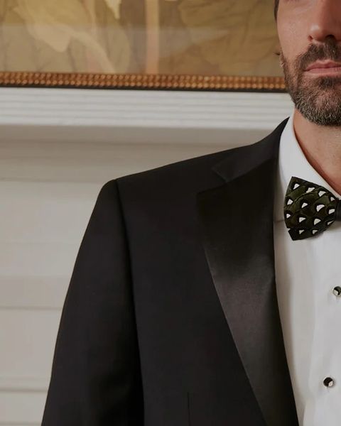 a man wearing a suit and brackish feather bow tie