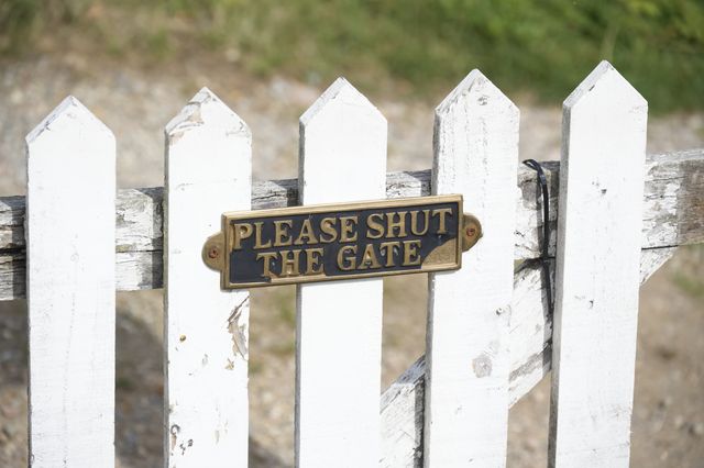 please close gate sign on white wooden fence uk