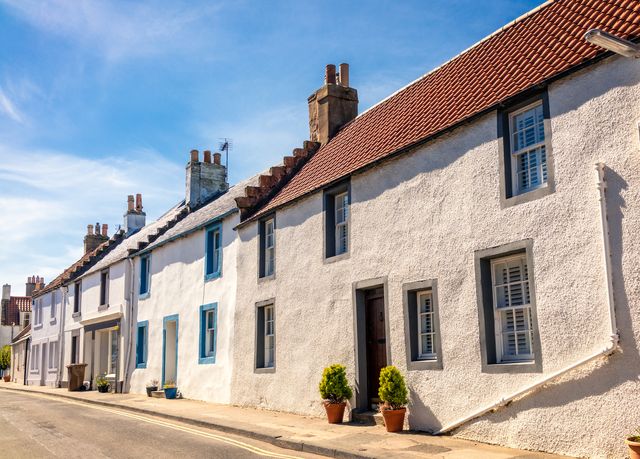a row of old fashioned cottages on a street near the sea, in the scottish seaside town of elie, fife