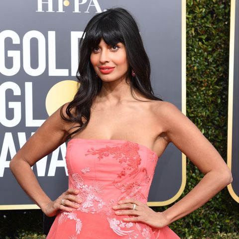 A photo of Jameela Jamil at an awards ceremony in a strapless pink dress, smiling on the red carpet.