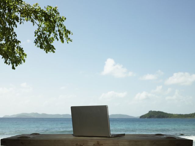 british virgin islands, tortola, laptop on bench beside sea