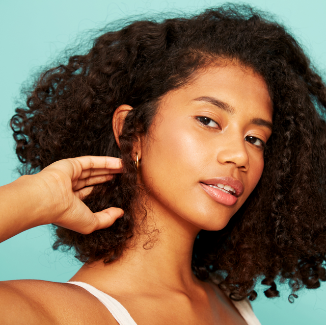 best moisturizing hair sprays   photo of a young woman brushing her naturally curly hair back behind her ear