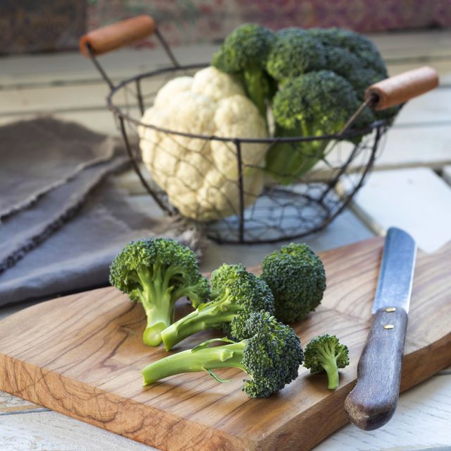 broccoli florets and kitchen knife on wooden board
