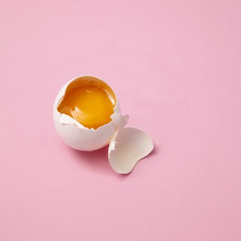 Broken egg on pink background