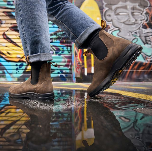 man walking through puddle in an alley filled with graffiti wearing blundstone 2056 men's all terrain chelsea boots in rustic brown