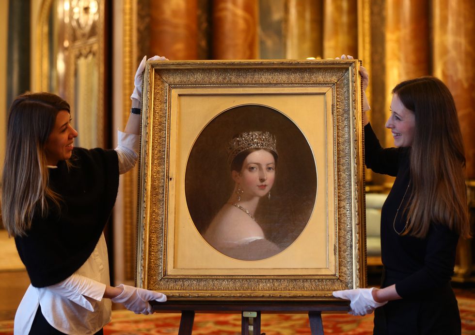 buckingham-palace-staff-holding-a-portrait-of-queen-news-photo-1134394184-1554218088.jpg