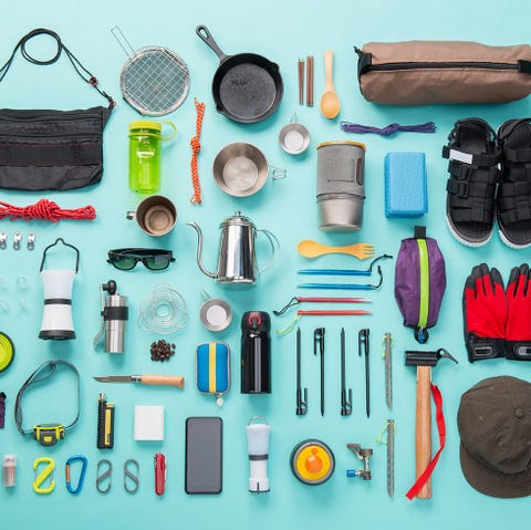 bug out bag supplies, including fanny pack, rope, sandals, cooking supplies and more on blue backdrop