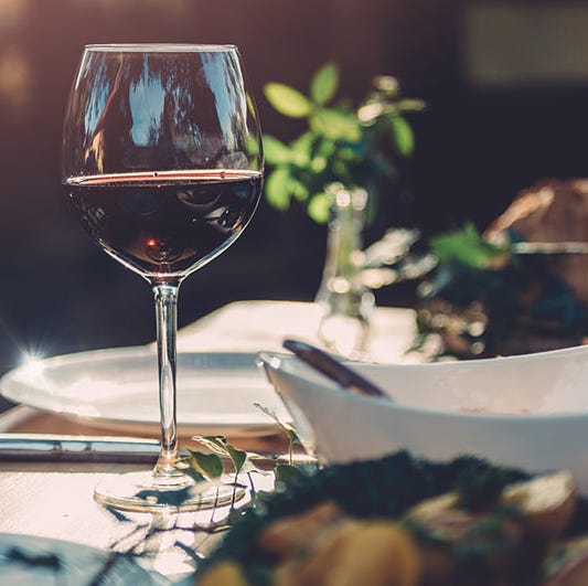 Glass of wine at dining table glass of red wine at dining table in backyard patio