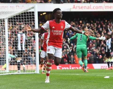 bukayo saka celebrates a goal in one of Arsenal's Premier League matches, he jogs along the side of the pitch away from the goal with his arms outstretched and smiling with joy