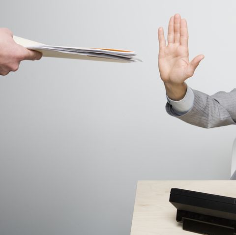 businessman holding hand up to paperwork