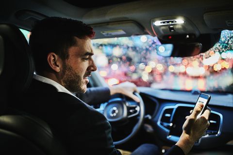 businessman looking at smartphone in car before departing on evening commute