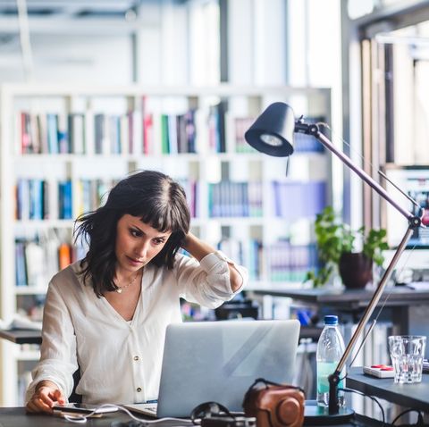 businesswoman looking at laptop while sitting in office