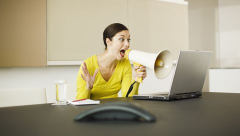 vrouw schreeuwt met megafoon tegen laptop