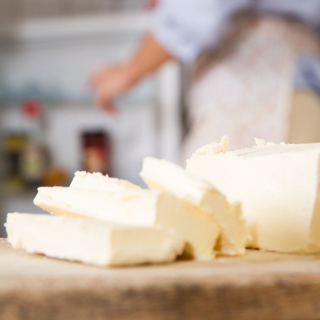 butter slices on a cutting board with a woman wearing an apron in the background