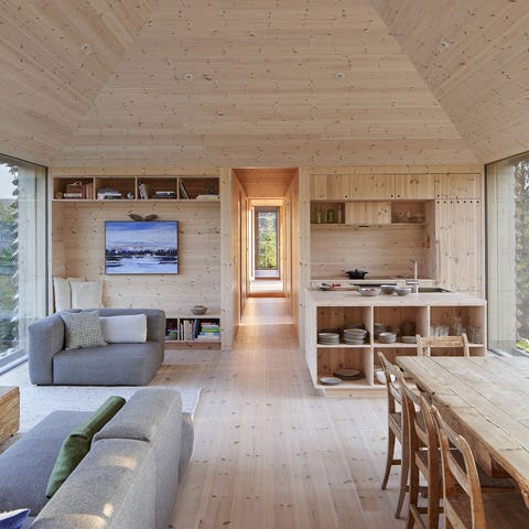 Salón comedor de madera con ventanales y sofás modulares en color gris