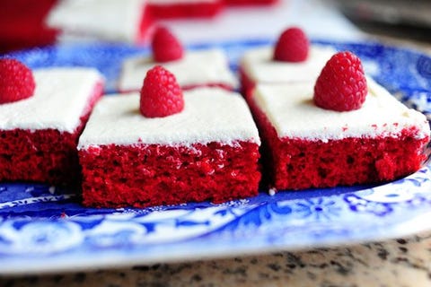 red velvet sheet cake slice on blue plate with raspberry on top