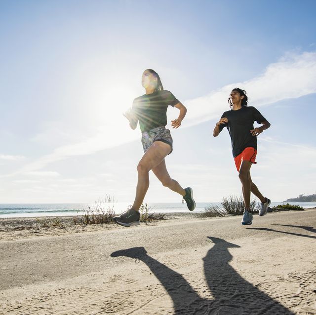 usa, california, dana point, man and woman running together by coastline