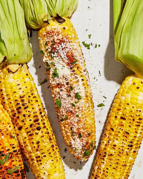 grilled mexican style corn arranged on a white wooden tray