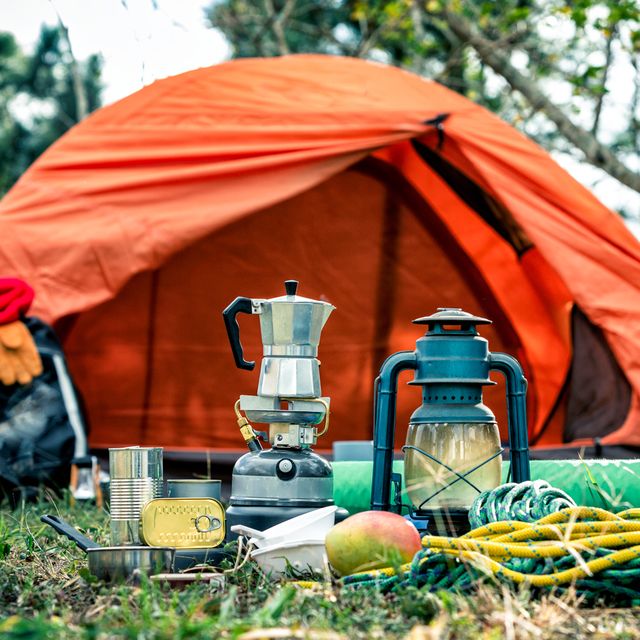 tent with camping lantern, coffee maker, hiking backpack, cooler, rope
