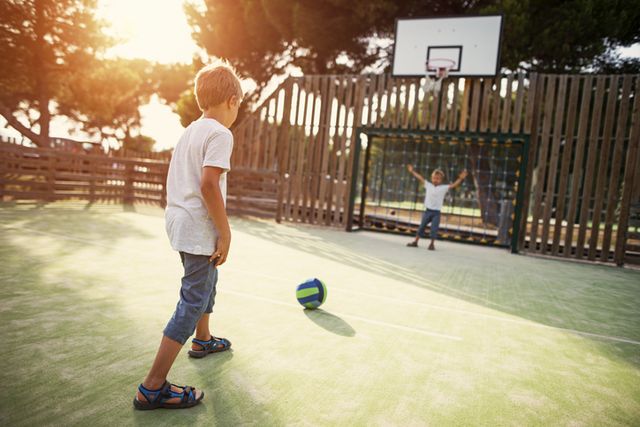 dos niños juegan al fútbol en un patio de colegio
