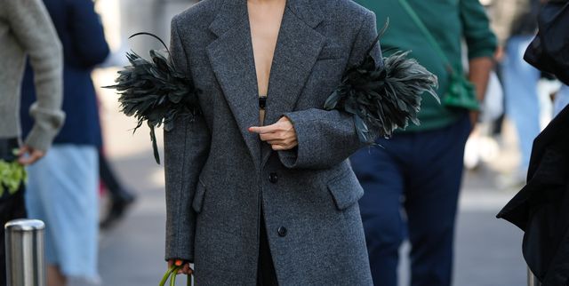milan, italy   september 22 a guest wears white sunglasses, a black bra underwear, a dark gray oversized blazer jacket with embroidered feathers sleeves, a dark gray knees pleated skirt, a green and black tie and dye print pattern shiny leather handbag from prada, white socks, black shiny leather block heels loafers from prada , outside prada, during the milan fashion week   womenswear springsummer 2023 on september 22, 2022 in milan, italy photo by edward berthelotgetty images