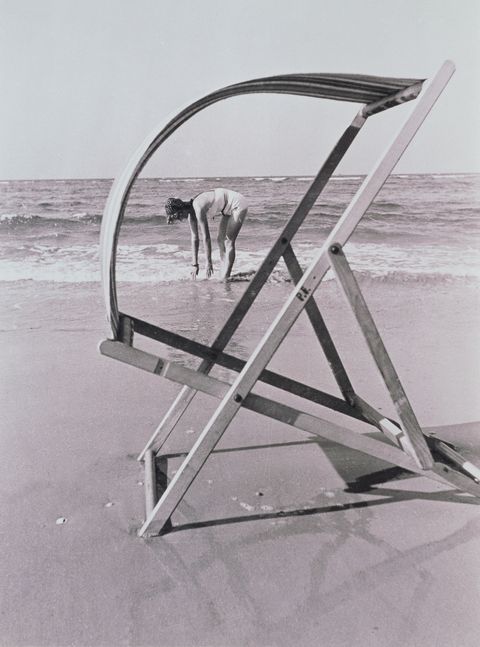 empty deck chair on beach with middle aged woman in sea photo by dr paul wolff  tritschlercorbis via getty images