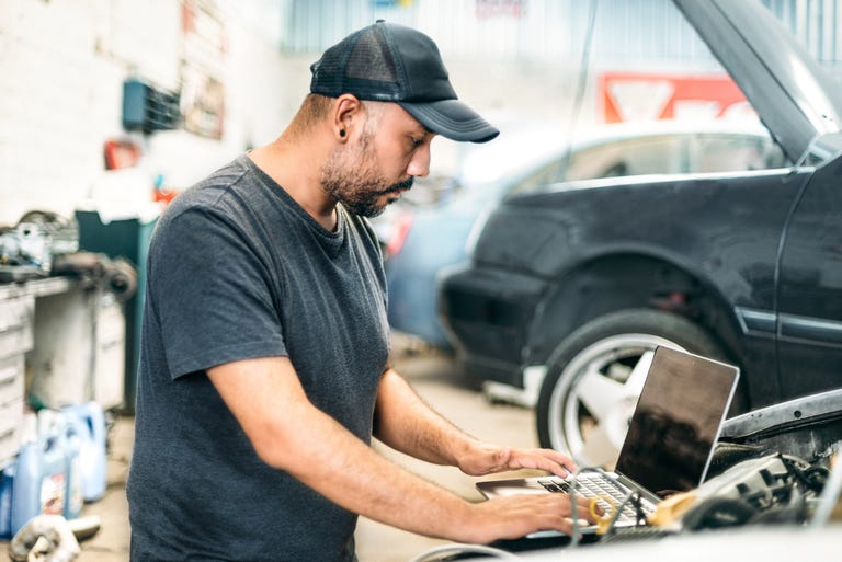 car mechanic using computer in auto repair shop
