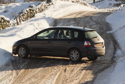 a car that skidded on ice on the kirkstone pass road above windermere after it was blocked by spindrift and wind blown snow, lake district, uk