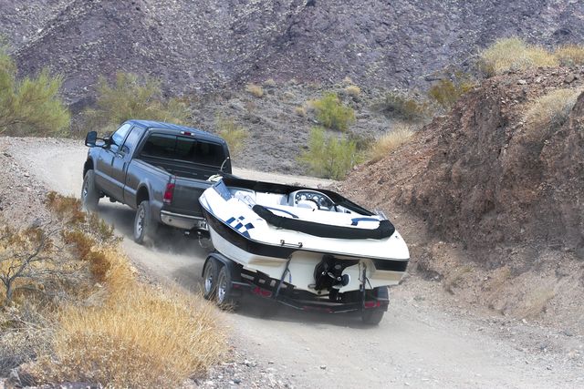 a car towing a boat through the dirt road
