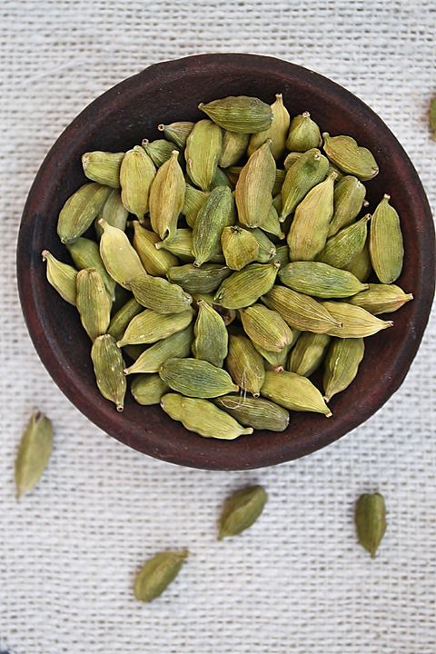 cardamom spice in a clay bowl against white background