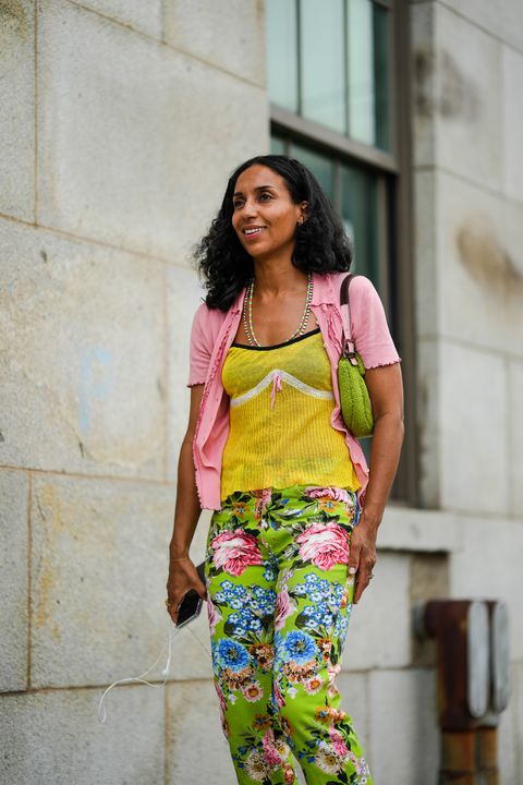 new york, new york   september 13 a guest wears a pale pink short sleeves wool cardigan, a yellow ribbed wool with black borders and white strap tank top, a pink and green pearls necklace, a white pearls long necklace, a green braided wool shoulder bag from fendi, green with purple  blue  pink  yellow flower print pattern straight pants, outside gabriela hearst, during new york fashion week, on september 13, 2022 in new york city photo by edward berthelotgetty images