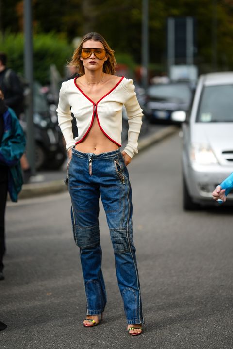 milan, italy   september 21 thora valdimars wears orange sunglasses, gold earrings, a white latte with small red borders zipper cardigan from diesel, navy blue embossed striped knees pattern pants from diesel, a silver shiny varnished leather handbag from diesel, green shiny strappy heels shoes , outside fendi, during the milan fashion week   womenswear springsummer 2023 on september 21, 2022 in milan, italy photo by edward berthelotgetty images