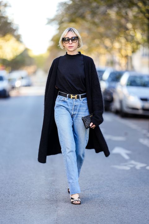 paris, france   october 14 emy venturini wears sunglasses from dita, a black turtleneck top from zara, a black wool long cardigan from cos, a hermes belt with logo buckle, blue denim ripped jeans pants from levis, a black leather quilted miu miu bag  clutch, black bejeweled shoes from miu miu, on october 14, 2021 in paris, france photo by edward berthelotgetty images