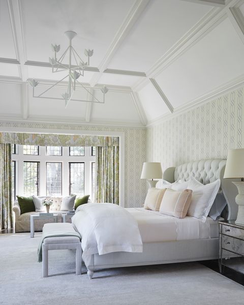 matouk linens dress an upholstered winged bed with   a painted wood frame