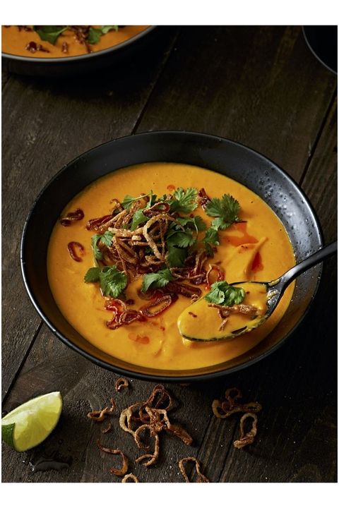 bowl of carrot ginger soup garnished with cilantro and fried shallots