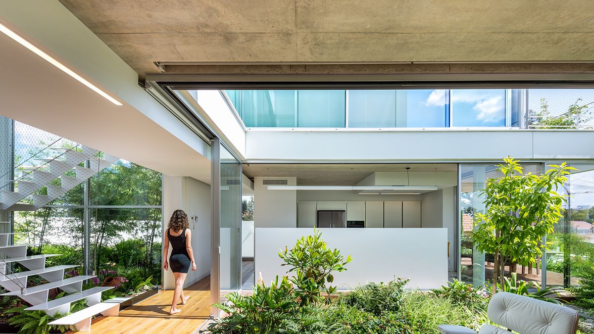 Una casa con una arquitectura moderna y espacios abiertos a un patio con  jardín