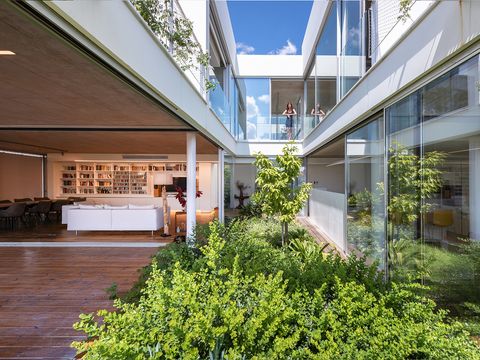 Una casa con una arquitectura moderna y espacios abiertos a un patio con  jardín