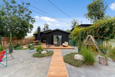 casa con fachada negra y jardín con tarima de madera