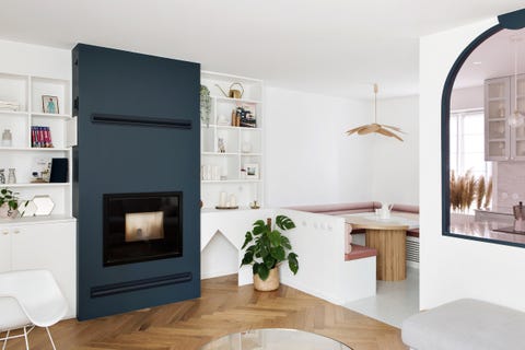 salón abierto con librería de obra blanca y chimenea empotrada en tabique pintado de azul