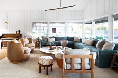 salón con sofá rinconera azul, butacas de piel y mesa de centro de madera