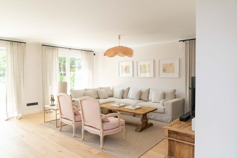 salón con sofá rinconera gris, mesa de centro de madera, butacas clásicas y lámpara de techo con pétalos