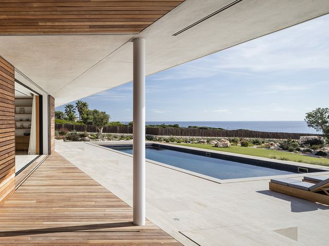 una casa en menorca con piscina, patio y espacios abiertos al mar