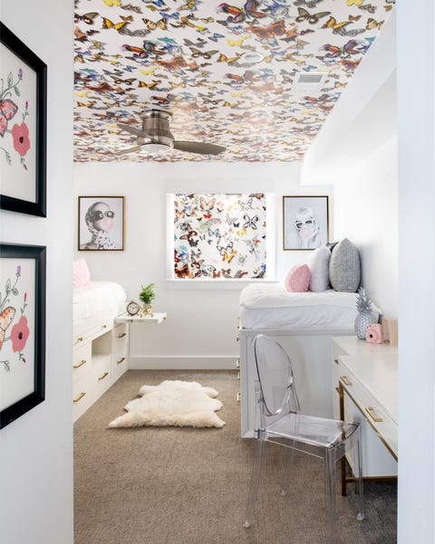 habitación infantil con dos camas nido y techo con papel pintado con mariposas