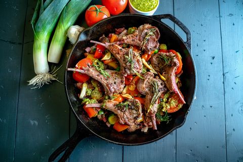cast iron skillet filled with gourmet lamb chops and a vegetable medley of brussels sprouts, bell pepper, garlic, leeks tomato, garlic and pesto