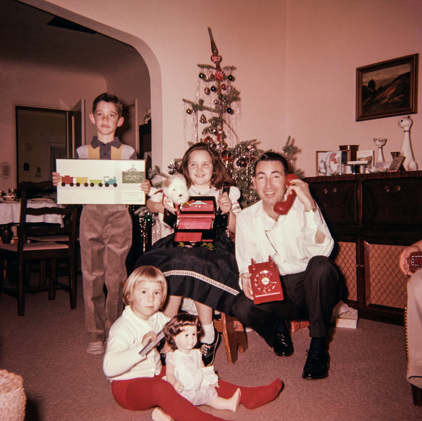 Padre caucásico con hijo e hijas posando con regalos de Navidad