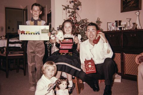 Caucasian father with son and daughters posing with Christmas gifts